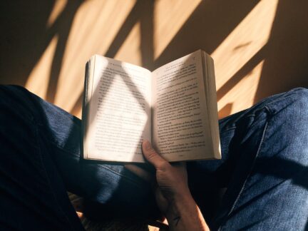 Photo of person sitting down reading with sunlight by Blaz Photo