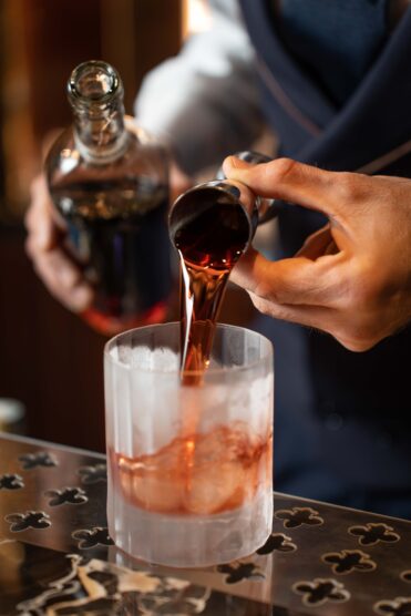 Bartender pouring negroni cocktail