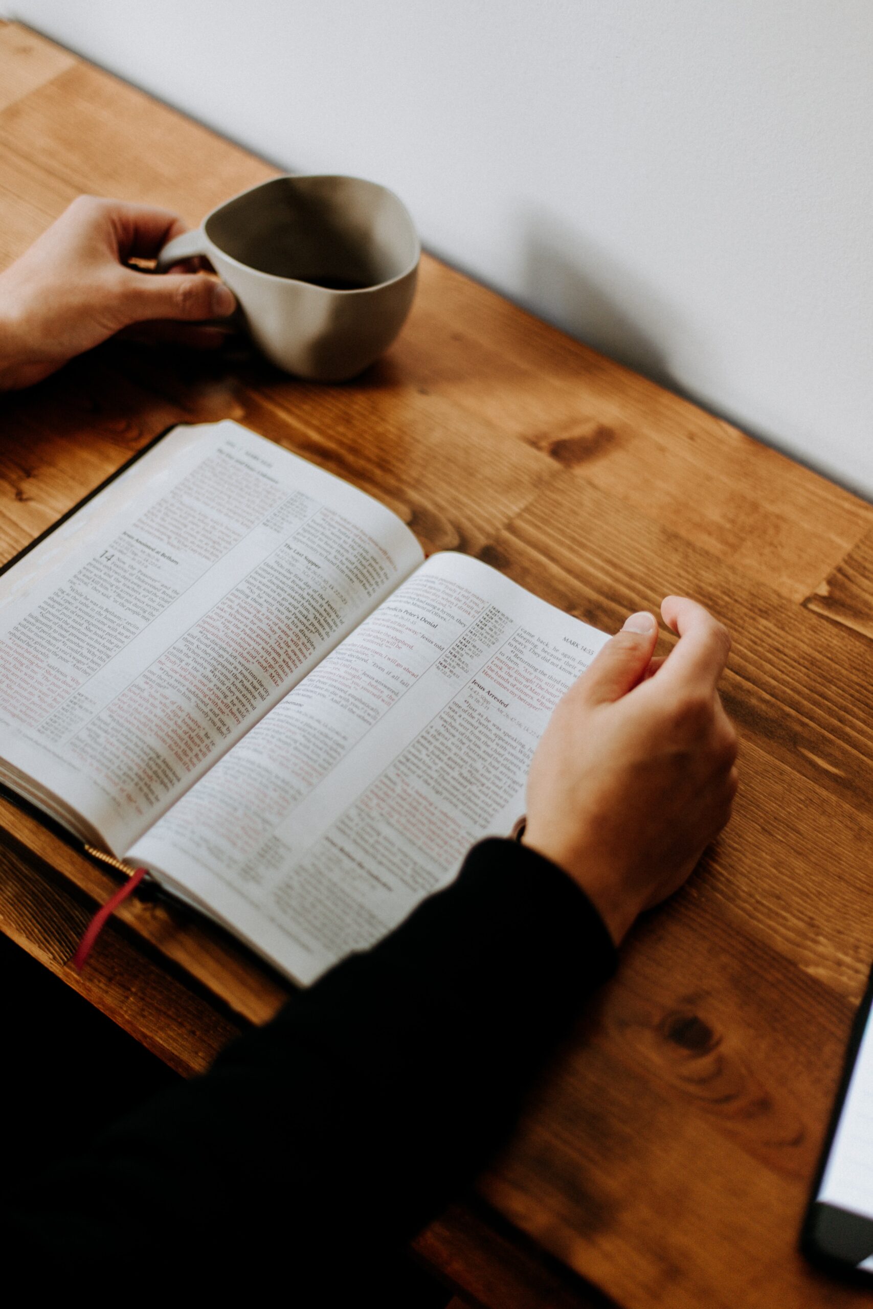 Man reading book holding ceramic pottery cup